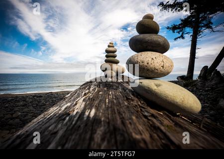 Spielen Sie mit Steinen auf einem Baumstamm am Agate Beach, Haida Gwaii, British Columbia, Kanada. Stockfoto