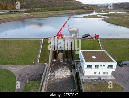 PRODUKTION - 01. November 2023, Hessen, Bad Soden-Salmünster: Ein Bagger steht auf dem Wehr des Kinzigtaler Damms (Luftaufnahme mit Drohne). Nach dem Austausch der defekten Dammtore sollte der Tank in den kommenden Monaten wieder mit Wasser gefüllt werden. (Zu dpa 'Arbeiten am Kinzig-Damm bald abgeschlossen - Staudamm kann beginnen') Foto: Boris Roessler/dpa Stockfoto