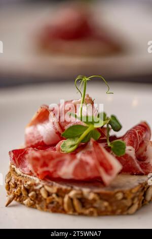 Geräucherte Speckscheiben auf Roggenbrot, Sandwich mit Schinken Stockfoto