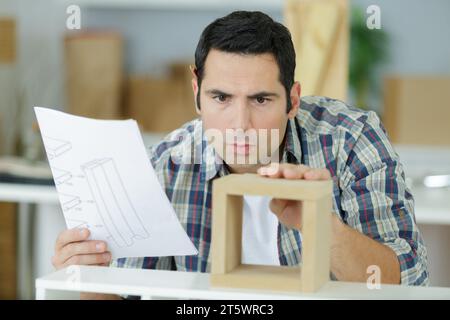 Erfahrener Zimmermann, der in der Werkstatt Unterlagen überprüft Stockfoto