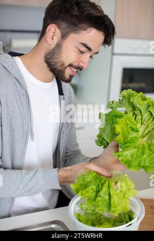 Ein sportlicher Mann bereitet in der Küche einen Salat zu Stockfoto
