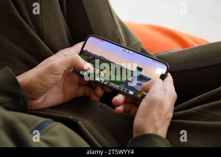 Minecraft mobiles iOS-Spiel auf dem iPhone 15 Smartphone-Bildschirm in männlichen Händen während des mobilen Gameplays. Mobiles Gaming und Entertainment auf einem tragbaren Gerät Stockfoto