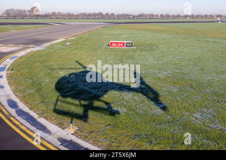 Schatten vom Starthubschrauber auf Gras in der Nähe der Start- und Landebahn des niederländischen Flughafens Zestienhoven in der Nähe von Rotterdam Stockfoto