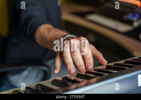 Nahaufnahme der Hände eines Musikers, die auf einer elektronischen Tastatur spielen, mit Fokus auf Finger und Tasten, um das Wesen der Musikkreation festzuhalten. Stockfoto