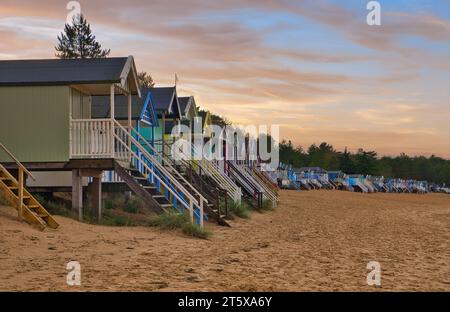 Ein wunderschöner Wintersonnenuntergang über den berühmten, farbenfrohen Strandhütten in Wells Next the Sea an der Küste von Nord-Norfolk. Stockfoto