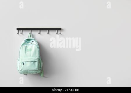 Stilvoller Schulrucksack an weißer Wand im Zimmer Stockfoto