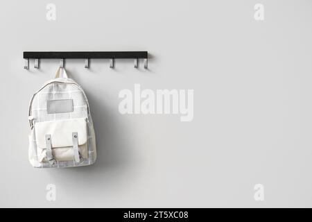 Stilvoller Schulrucksack an weißer Wand im Zimmer Stockfoto
