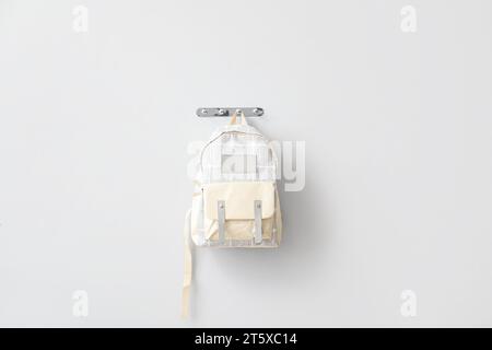 Stylischer Schulrucksack, der an einer hellen Wand hängt Stockfoto