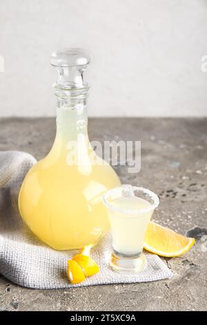 Flasche und Schuss leckerer Limoncello auf grauem Tisch Stockfoto