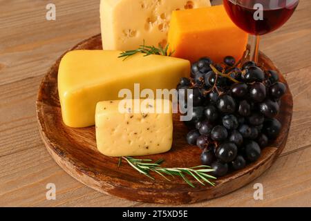 Teller mit leckerem Käse und Trauben auf hölzernem Hintergrund Stockfoto