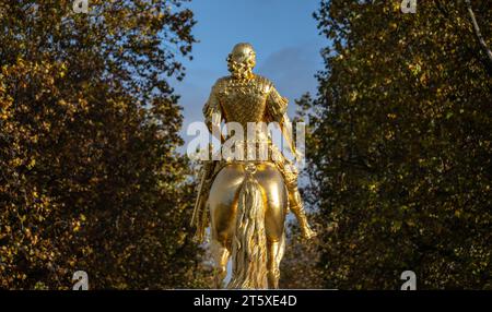 Dresden, Deutschland. November 2023. Am Morgen scheint die Sonne auf den „Goldenen Reiter“, die überlebensgroße Reiterstatue des sächsischen Kurfürsten Augustus des Starken (1670-1733) aus dem 18. Jahrhundert. Die herbstfarbenen Blätter der Bäume auf der Hauptstraße sind im Hintergrund zu sehen. Robert Michael/dpa/Alamy Live News Stockfoto