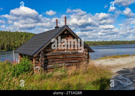 Holzblockhaus am Ufer des Öst-Kieratjärn-Sees, umgeben von Nadelwäldern. Jokkmokk, Norrbotten, Polarkreis, Schweden Stockfoto