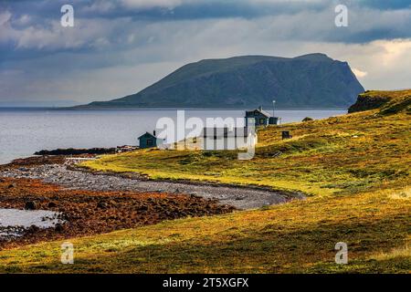 Isolierte Häuser an der Meerenge zwischen der Insel Magerøya und dem Festland. Im Hintergrund die Insel Store Altsula. Norwegen Stockfoto