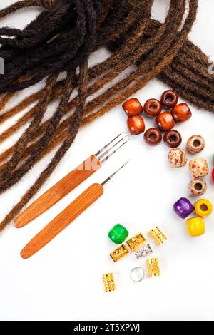 Haarhäkelnadeln und dekorative Perlen für Dreadlocks und Zöpfe auf weiß Stockfoto