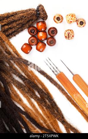 Haarhäkelnadeln und dekorative Perlen für Dreadlocks und Zöpfe auf weiß Stockfoto