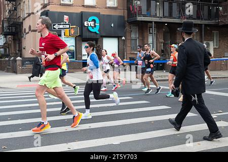 Ein orthodoxer jüdischer Mann überquert die Straße und vermeidet die Anzahl der Läufer beim New York Marathon 2023. In Williamsburg, Brooklyn Stockfoto