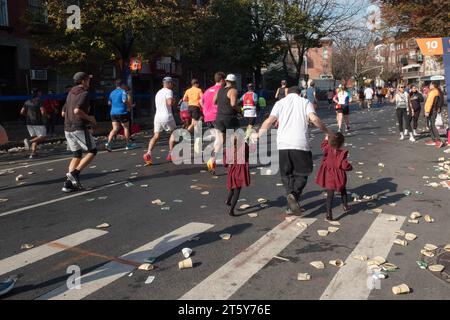 Ein orthodoxer jüdischer Vater und seine zwei gleichgekleideten Töchter nehmen am NYC Marathon-Rennen Teil. Auf der Bedford Avein Williamsburg direkt nach einer Wasserstation. Stockfoto