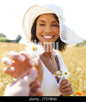 Porträt, Blumen oder pov einer glücklichen Frau auf einem Feld, auf dem Land oder in der Natur im Sommer, um sich in der Pause zu entspannen. Hände, Wellness oder birassische weibliche Person in A Stockfoto