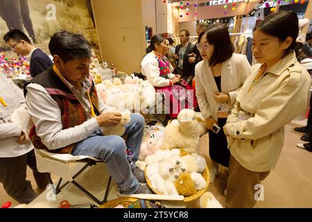 (231107) -- SHANGHAI, 7. November 2023 (Xinhua) -- der peruanische Handwerker Mamani stellt am Stand der Warmpaca während der 6. China International Import Expo (CIIE) im ostchinesischen Shanghai am 7. November 2023 Spielzeug mit Alpakapelz her. Auf der ersten China International Import Expo (CIIE) führte Ma Yuxia, eine chinesische Geschäftsfrau, die Plüschalpakas des peruanischen Handwerkers Mamani auf den chinesischen Markt ein. MA und ihre Partner mieteten auf der ersten CIIE einen Stand von nur 9 Quadratmetern, um diese Spielzeuge und andere traditionelle Handwerkskunst aus Peru zu präsentieren und zu bewerben. Sie stellten auch einen eigenen BH her Stockfoto