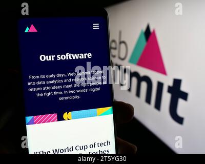 Person, die ein Mobiltelefon hält und die Webseite des jährlichen Technologiekonferenz Web Summit (Lissabon) vor dem Logo zeigt. Konzentrieren Sie sich auf die Mitte des Telefondisplays. Stockfoto