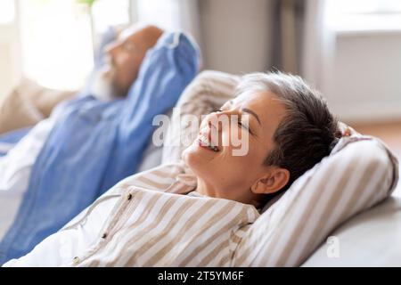 Lächelndes Seniorenpaar, Das Sich Zu Hause Auf Einem Bequemen Sofa Ausruht Stockfoto