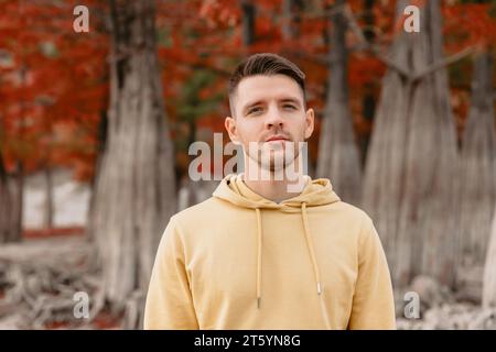 Schöner Mann im herbstlichen Wald. Kaukasier in gelben Kapuzenpullis Stockfoto