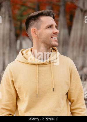 Schöner Mann im herbstlichen Wald. Lächelnder kaukasier in gelben Hoodies Stockfoto