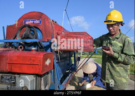 VIETNAM, Provinz Yen Bai, Cam Nhan, Landwirt dreschen Reis nach der Ernte mit kleiner mobiler Dreschmaschine / Gemeinde Cam Nhan, Dreschmaschine für Reis, Kleinbauern dreschen Reis nach der Ernte Stockfoto