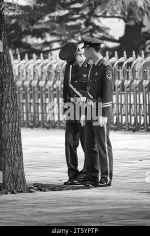 Schwarzweiß-Foto von zwei Soldaten der Volksbefreiungsarmee, die in der Nähe des Tiananmen-Platzes in Peking, China, sprechen. Stockfoto