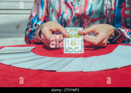 Unerkennbare kaukasische Frau, die zu Hause sitzt und Tarotkarte auf dem Tisch zeigt, während der Sitzung ihrem Klienten, Kopierraum. Stockfoto