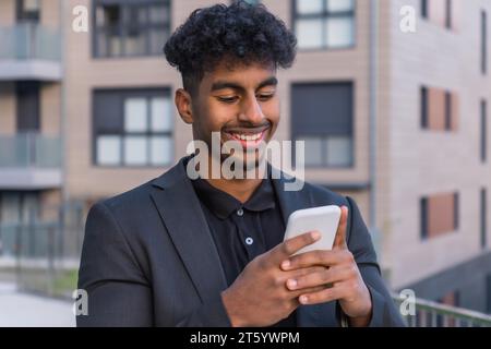 Porträt eines glücklichen arabischen Geschäftsmannes, der vor einem Gebäude telefoniert Stockfoto