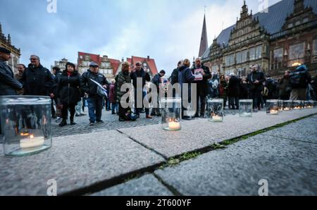 Bremen, Deutschland. November 2023. Teilnehmer einer Gedenkfeier für die Opfer des Terroranschlags der Hamas auf Südisrael stehen hinter Kerzen auf dem Bremer Marktplatz. Hunderte von Menschen waren gekommen, um vor dem Bremer Parlament zu gedenken. Quelle: Focke Strangmann/dpa/Alamy Live News Stockfoto