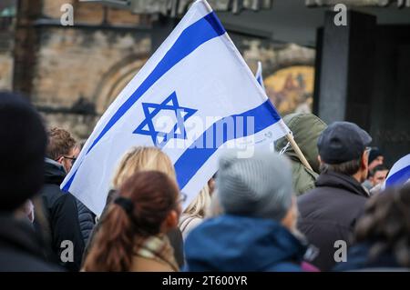 Bremen, Deutschland. November 2023. Ein Teilnehmer an einer Gedenkveranstaltung für die Opfer des Terroranschlags der Hamas auf Süd-Israel auf dem Bremer Marktplatz hält eine Flagge des Staates Israel. Hunderte von Menschen waren gekommen, um vor dem Bremer Parlament zu gedenken. Quelle: Focke Strangmann/dpa/Alamy Live News Stockfoto