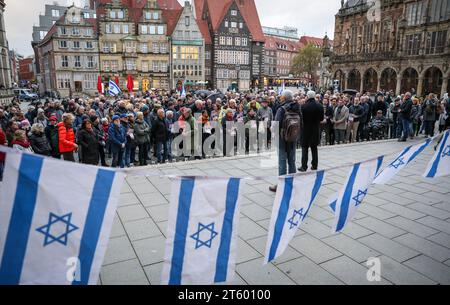 Bremen, Deutschland. November 2023. Teilnehmer einer Gedenkveranstaltung für die Opfer des Terroranschlags der Hamas auf Südisrael stehen hinter den Flaggen des Staates Israel auf dem Bremer Marktplatz. Hunderte von Menschen waren gekommen, um vor dem Bremer Parlament zu gedenken. Quelle: Focke Strangmann/dpa/Alamy Live News Stockfoto