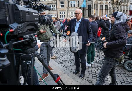 Bremen, Deutschland. November 2023. Andreas Bovenschulte (2. V. R.), Präsident des Bremer Senats und Bürgermeisters, gibt ein Interview am Rande einer Gedenkfeier für die Opfer des Terroranschlags der Hamas auf Süd-Israel auf dem Bremer Marktplatz. Hunderte von Menschen waren gekommen, um vor dem Bremer Parlament zu gedenken. Quelle: Focke Strangmann/dpa/Alamy Live News Stockfoto