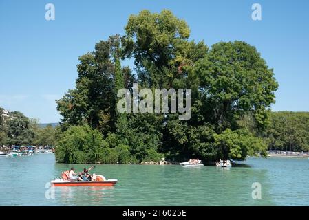 Touristen mit Tretboot, Tretboot oder Paddelboot & Île des Cygnes, oder Schwaneninsel, See Annecy oder Lac d'Annecy Haute-Savoie Frankreich Stockfoto