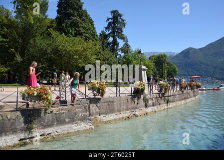 Touristen, die entlang des Quai Napoléon im Jardins de l'Europe am See oder am Ufer des Annecy Lake Annecy Haute-Savoie Frankreich spazieren Stockfoto