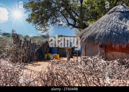 kraal, Lehmhütte mit Strohdach, Feuer brennt im Hof, Dorf Viehpfosten Gehöft im südlichen afrika, Schatten von einem Baobab Baum Stockfoto