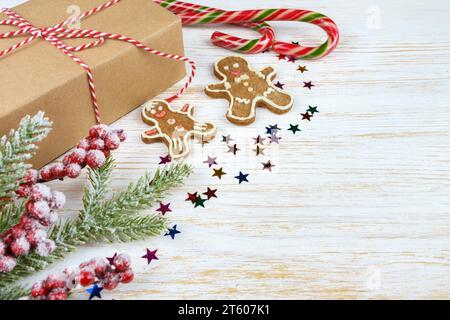 Neujahrshintergrund mit christbaumzweig, Lebkuchen-Mann und Geschenkbox auf weißem Holzhintergrund mit Kopierbereich. Flach liegend, Draufsicht. Stockfoto