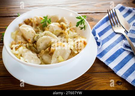 Ukrainischer Vareniky oder Pierogi gefüllt mit Kartoffeln und Pilzen, serviert mit gebratenen Zwiebeln. Holztischhintergrund. Hochwertige Fotos Stockfoto