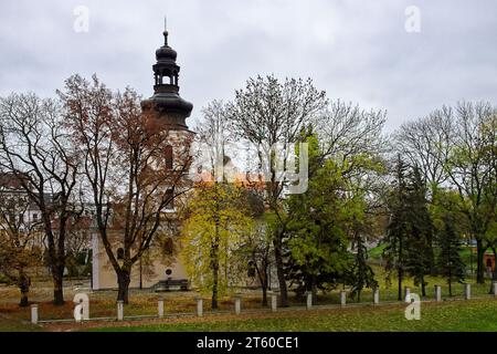 Römisch-katholische Kirche St. Nikolaus, Zamosc. Alte katholische Kirche umgeben von Herbstbäumen, Landschaft. Stockfoto