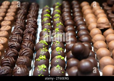 Auswahl an Schokoladenpralinen in der Konditorei. Verschiedene süße Schweizer oder belgische Süßigkeiten in Reihen. Handgemachte Desserts aus dunkler Schokolade und Milchschokolade Stockfoto