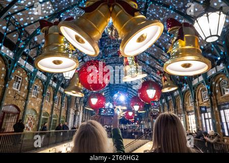 London, Großbritannien. 7. November 2023. Die Weihnachtsbeleuchtung von Covent Garden ist eingeschaltet. Zu den neuen Dekorationen im Market Building gehören 40 gigantische Glocken mit Bögen, 12 riesige Kugeln und acht sich drehende Spiegelkugeln. Auf der Piazza ist ein 60 Meter langer britischer Weihnachtsbaum mit 30.000 LED-Leuchten und mehr als 200 neuen riesigen Goldkugeln bedeckt. Quelle: Stephen Chung / Alamy Live News Stockfoto