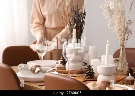 Frau, die einen Tisch mit getrockneten Blumen im Esszimmer legt Stockfoto