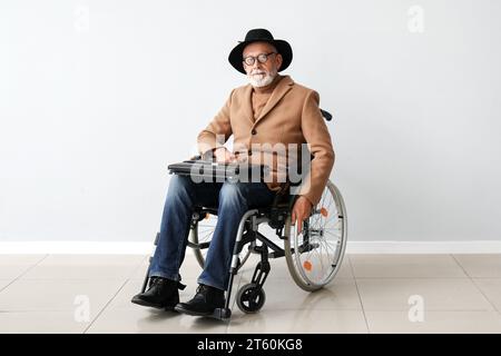 Seniorenmann im Rollstuhl in der Nähe einer Lichtwand Stockfoto