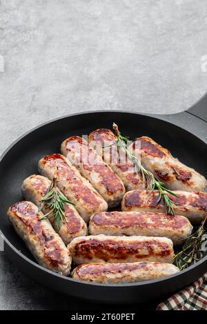 Köstliche Schweinefleischwürste in einer Pfanne auf grauem Hintergrund Stockfoto
