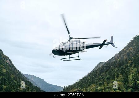 Ziviler Hubschrauber, der in den Himalaya-Bergen in der Nähe der Siedlung Kothe in Nepal HOCHFLIEGT. Mera Peak Klettertour. Sicherheit im Luftverkehr Stockfoto