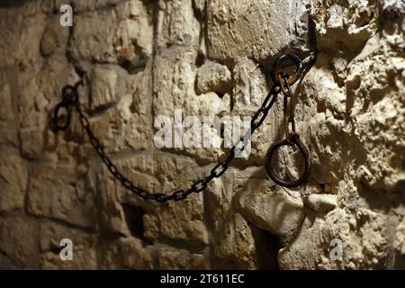 Sklaverei und Knechtschaft starke Stahlfesseln an der Steinmauer im Burgkeller oder Grabmal Stockfoto