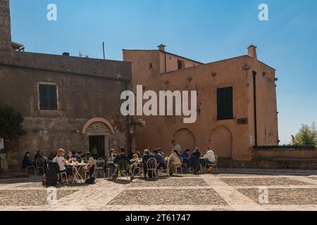 Menschen in einem Café im Freien auf der Piazza Sant'Agostino, Zentrum des mittelalterlichen Dorfes an der italienischen Riviera, Borgio Verezzi, Savona, Ligurien, Italien Stockfoto