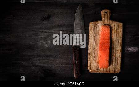 Filet roher Lachsfische auf einem Schneidebrett mit großem Küchenmesser, Draufsicht mit Kopierraum Stockfoto